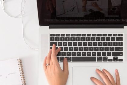 Les mains d'une jeune femme qui écrit un blog sur son ordinateur