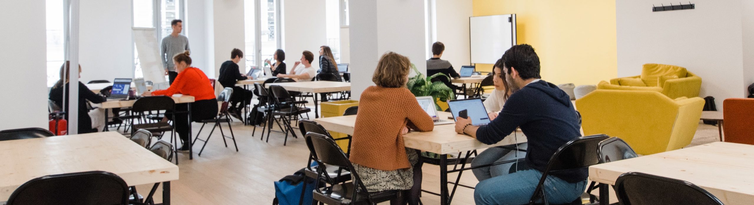 Plusieurs groupes d'entrepreneurs dans une grande salle de Schoolab