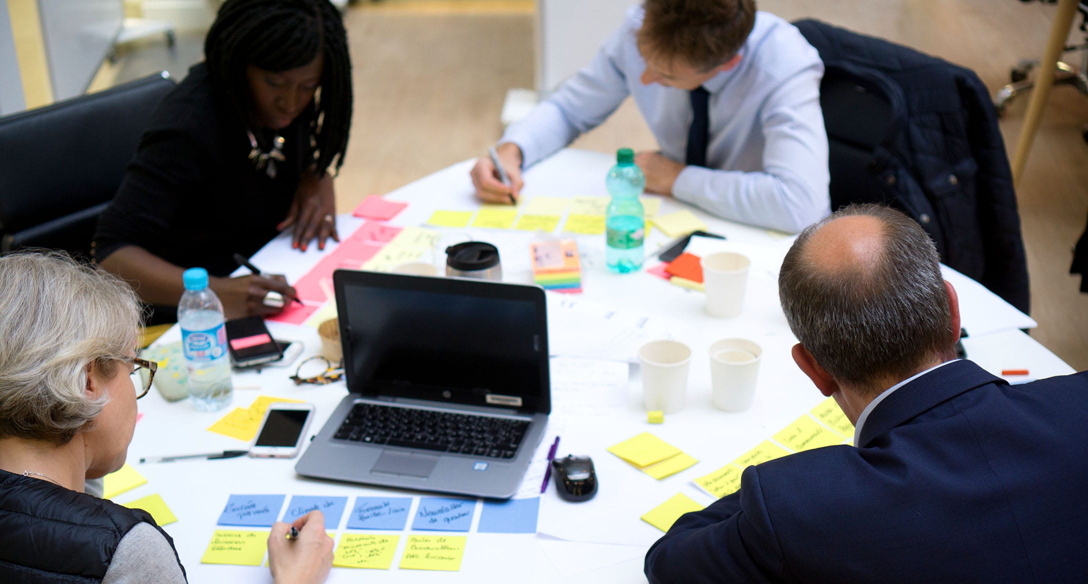 3 personnes travaillant sur une table remplie de post it