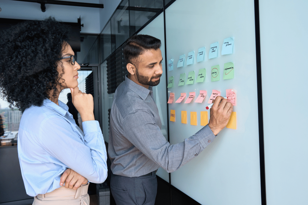 2 personnes entrain de réfléchir devant un tableau de post-it